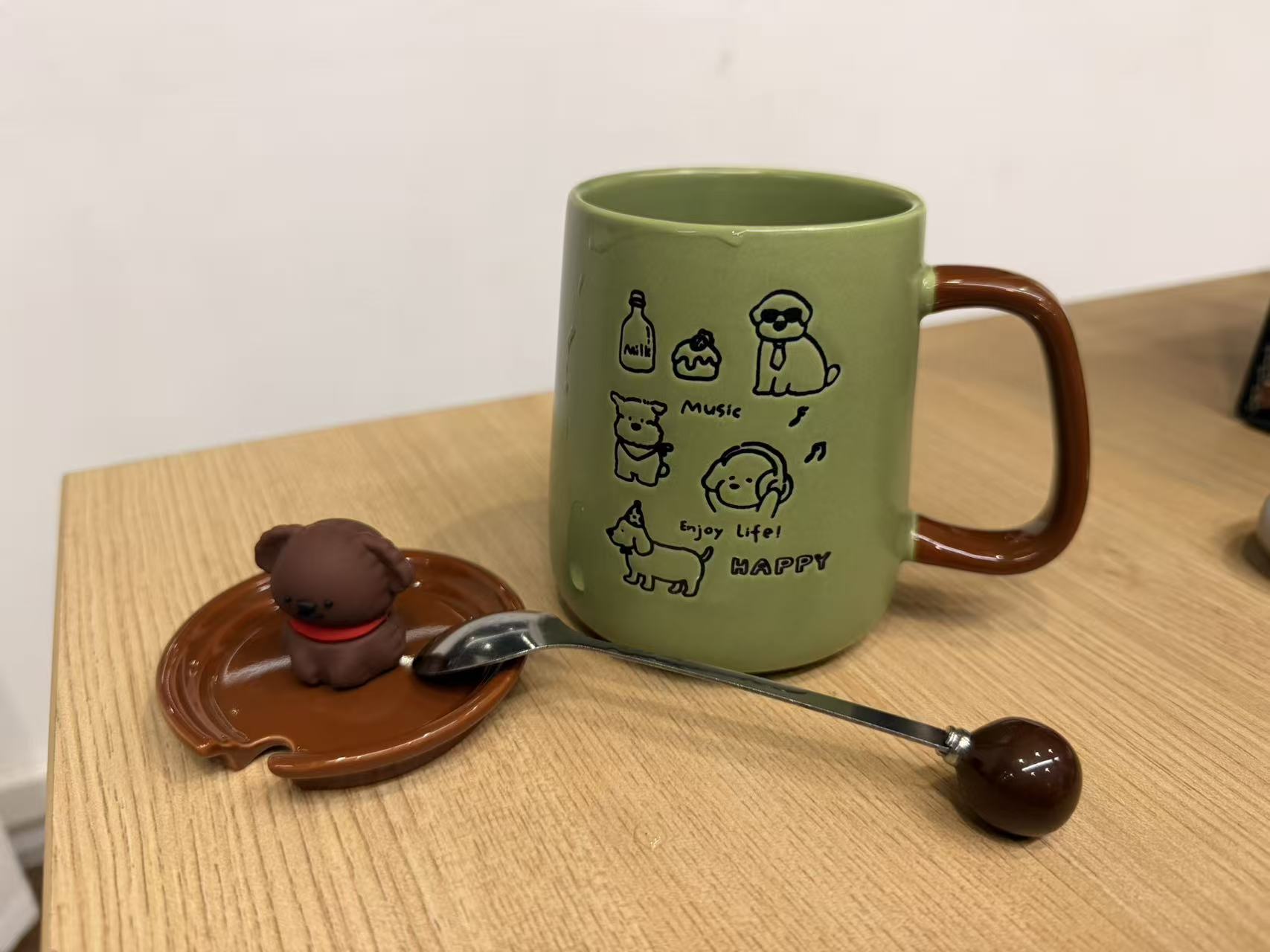 绿色小狗图案马克杯的商品实拍原图,杯盖与带棕色球端的长勺放在杯旁